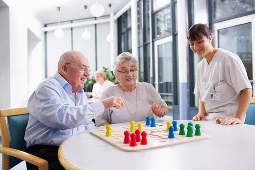 Pflegekraft und Senioren bei einem Spiel